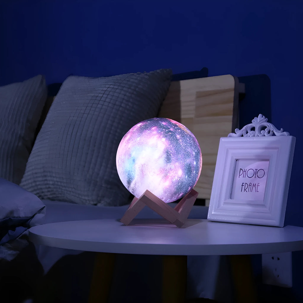 White 3D-printed moon lamp on a table showing crater details, with a remote control beside it.