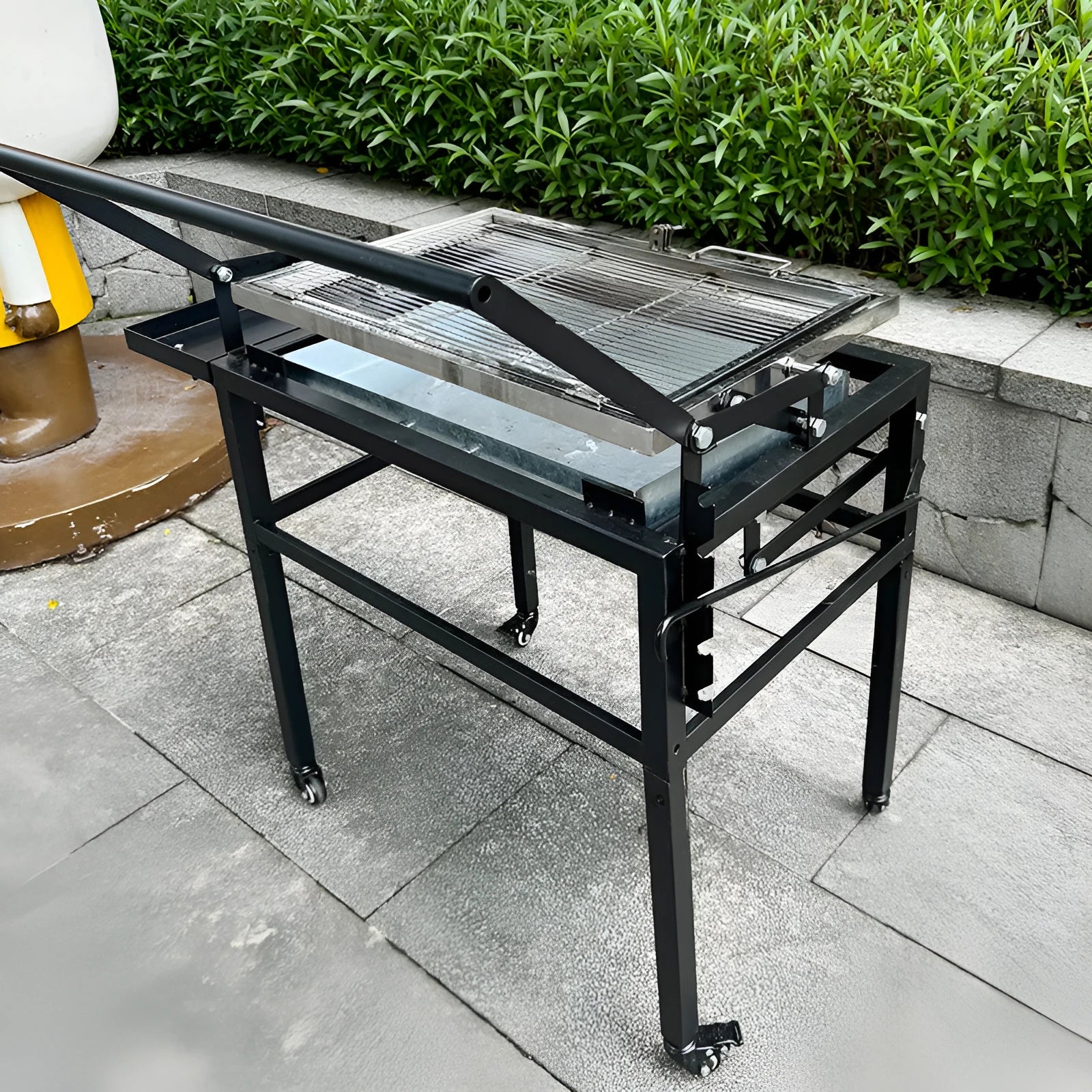 Large portable foldable charcoal barbecue grill stove shown in a garden setting