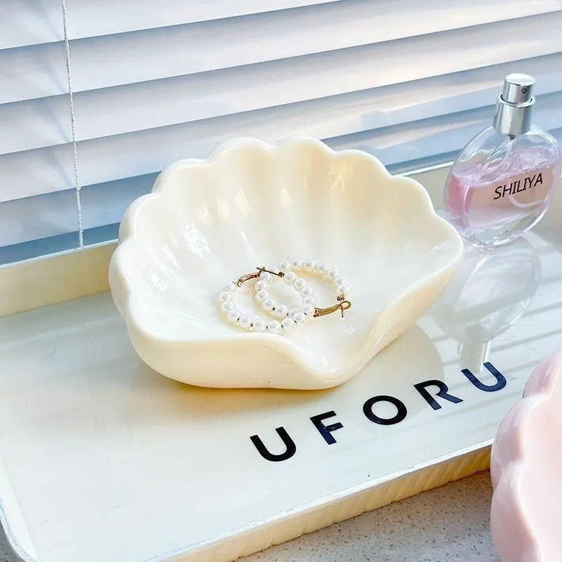 White and pink plastic shell-shaped soap dish for bathroom countertops.
