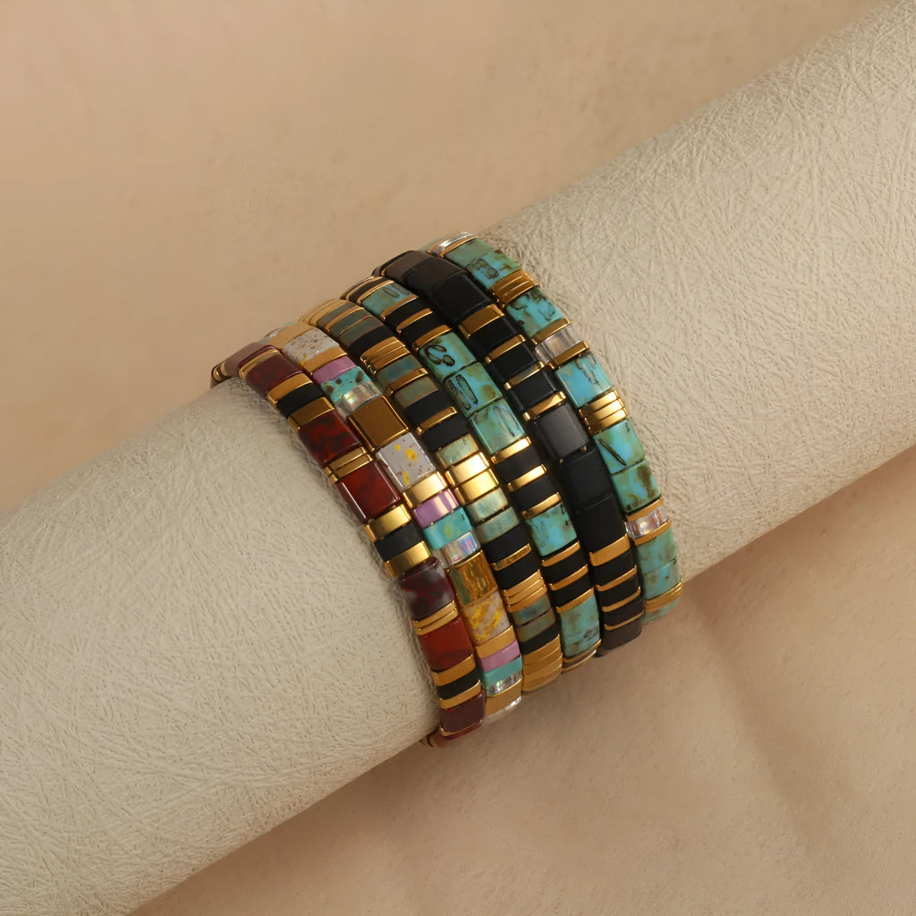 Geometric glass and coloured glaze beaded bracelet in milky white on a wrist.