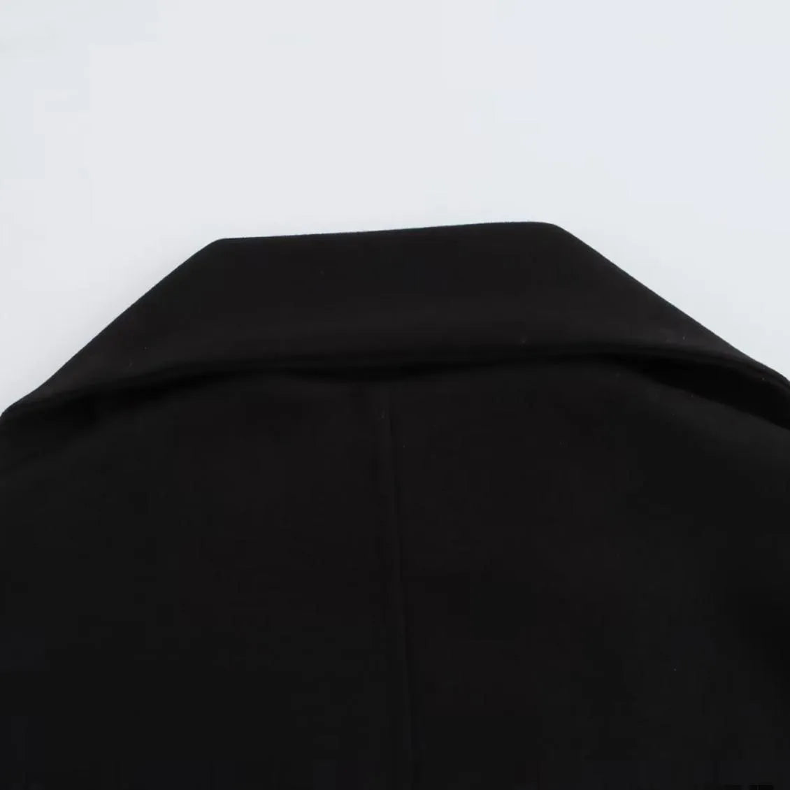 Women's long black polyester coat with a faux fur collar, shown in a street fashion style.