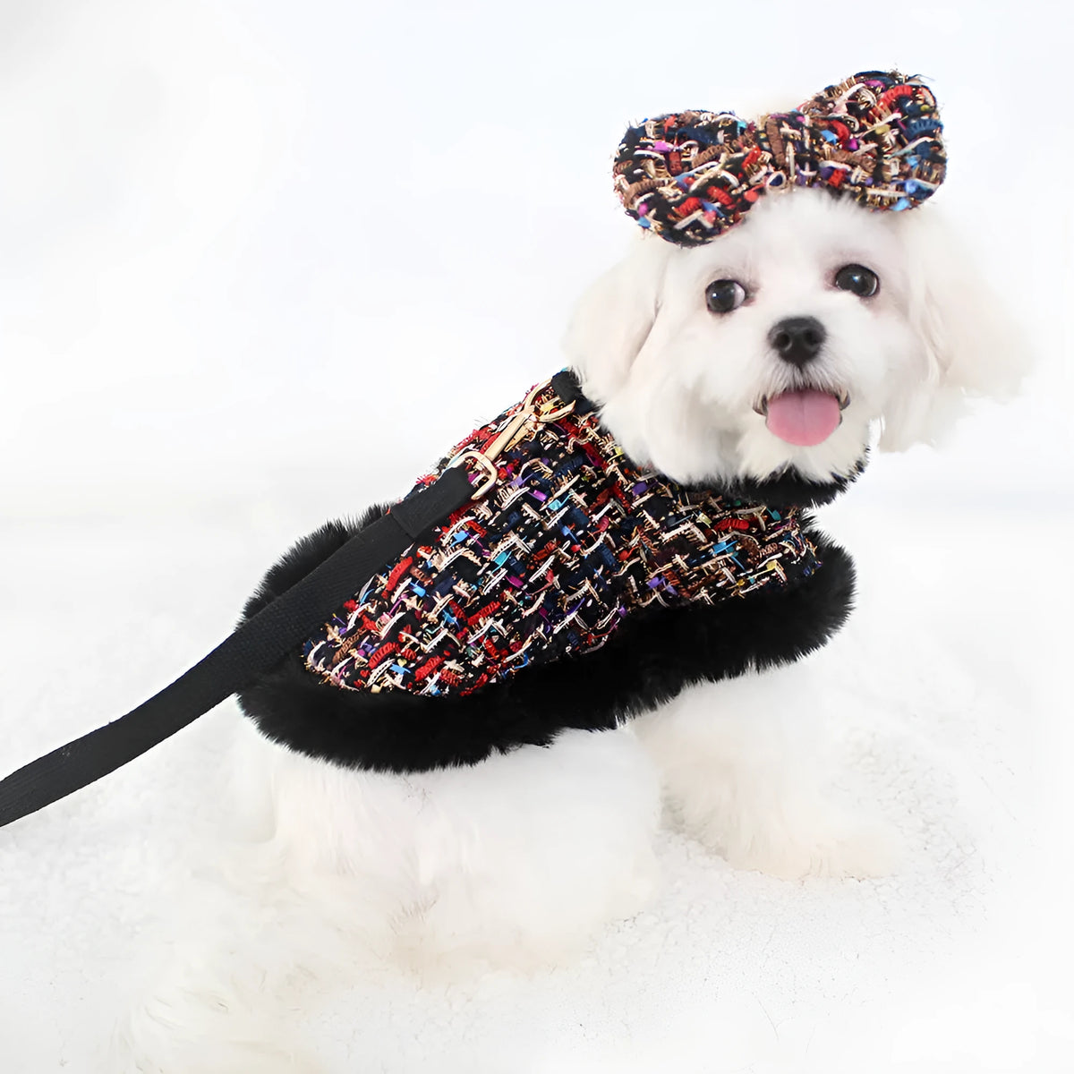 A dog wearing a classic cloth cloak chest harness with an attached hand holding rope.