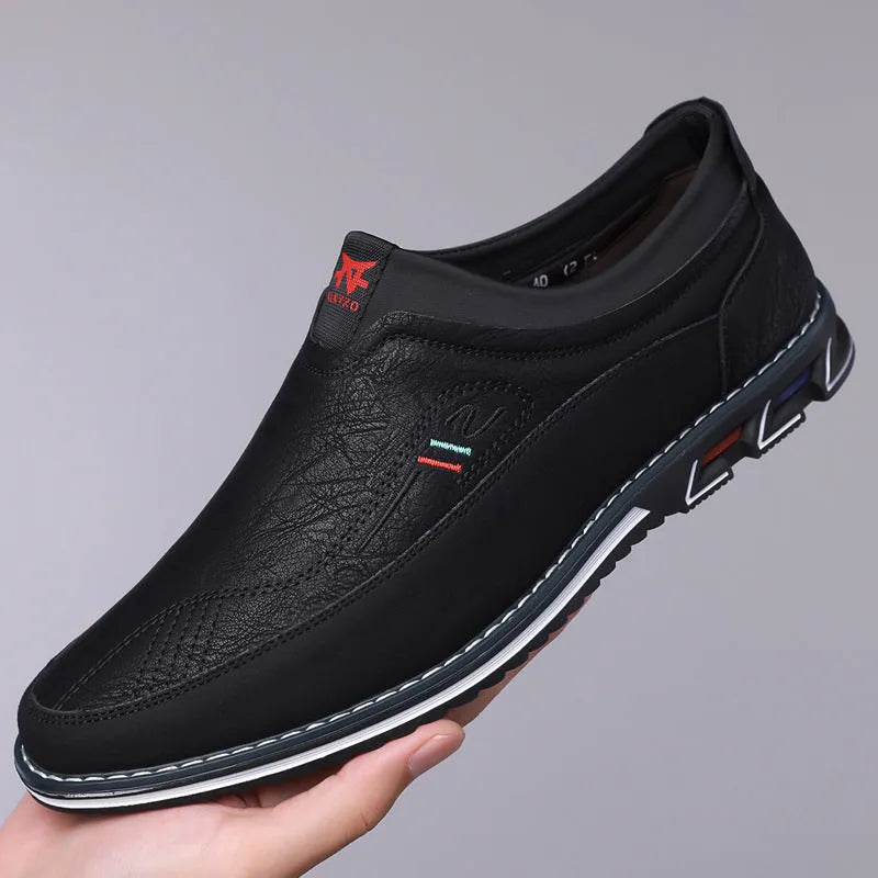 Men's black leather-toe casual shoes with a fabric upper and rubber sole on a plain background.