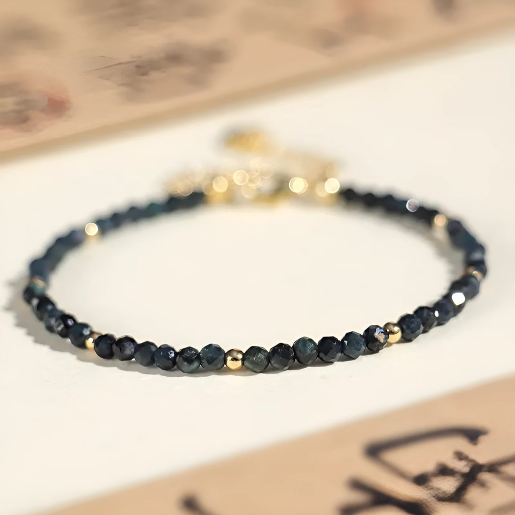 Close-up of a blue tourmaline beaded bracelet with metallic spacer beads on a woman's wrist.