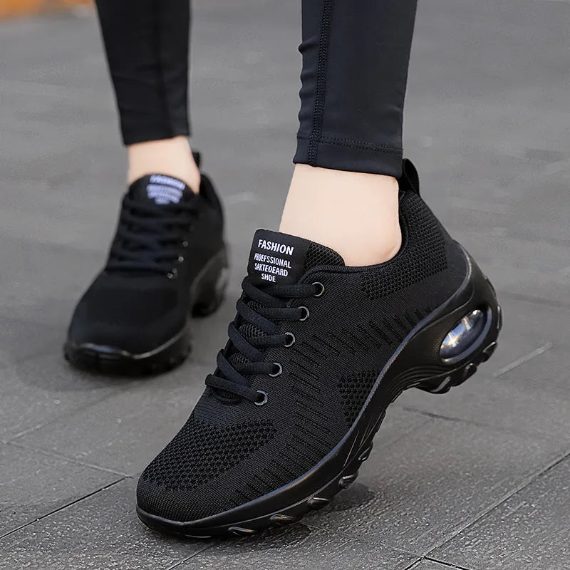 Women's black mesh sneakers with lace-up front and round toe, showing mid-heel height