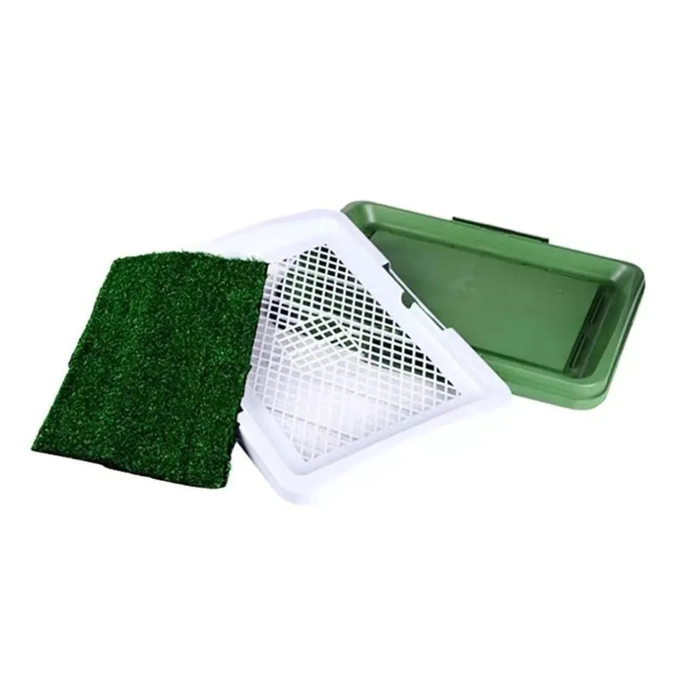 Green three-layer indoor dog toilet tray with artificial grass top, absorbent pad, and plastic drip tray base.