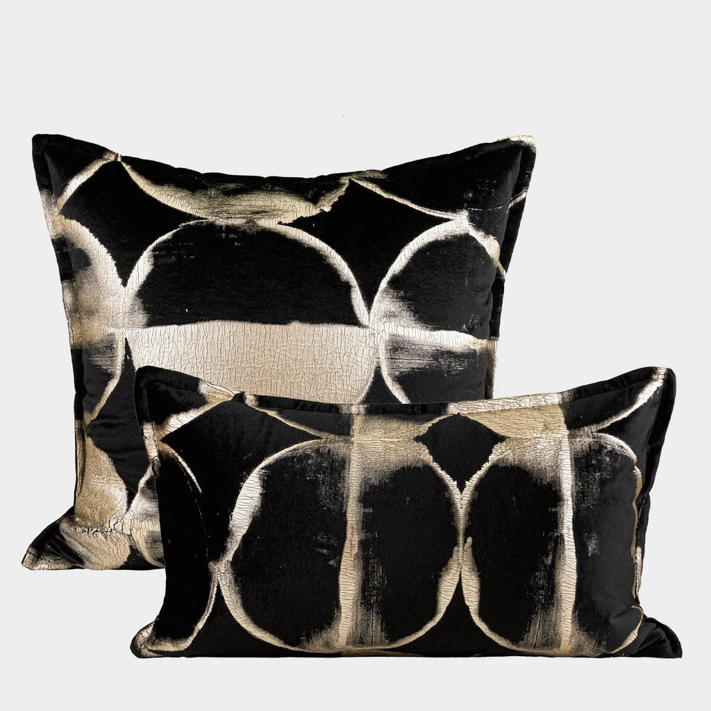 Black and gold abstract patterned square cushion on a grey sofa