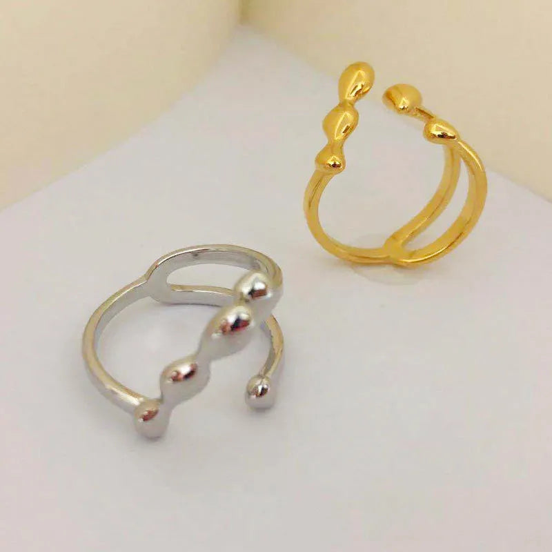 Brass opening ring with circle and sphere design in gold finish on finger