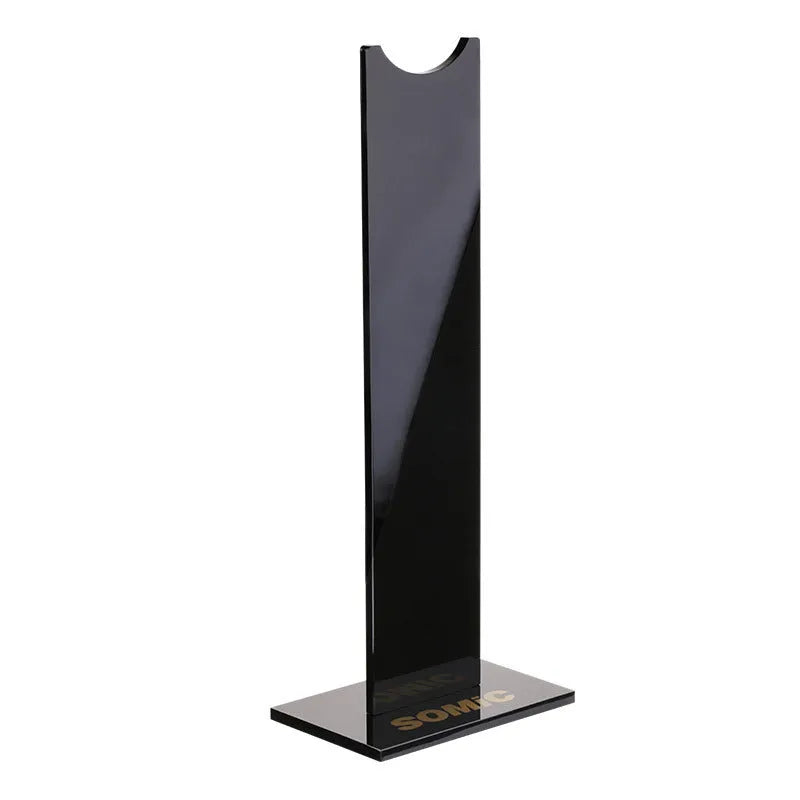 A black or pink detachable headphone stand for head-mounted gaming headsets on a desk.