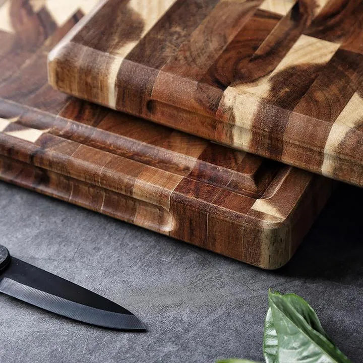 Brown solid acacia wood cutting board with 3cm thickness on a kitchen counter.