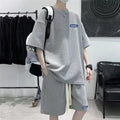Man wearing a waffle-textured grey short sleeve top and matching shorts from a leisure sports suit set.