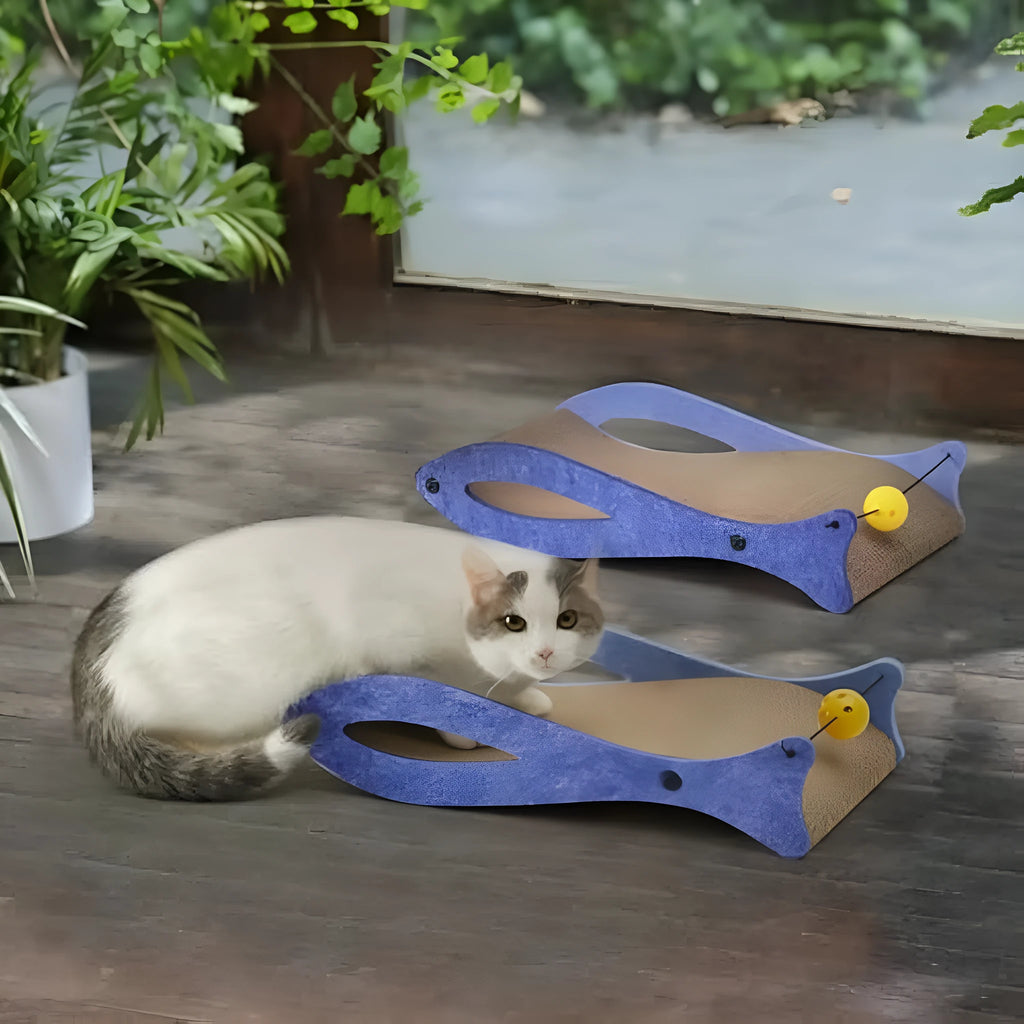 Blue fish-shaped cardboard cat scratcher with a bell toy on a string, shown on a flat surface.