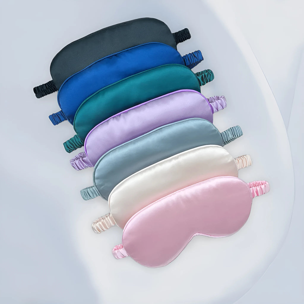 Double-sided silk-like sleep mask in rayon elastic satin shown in multiple colour options on a grey background.