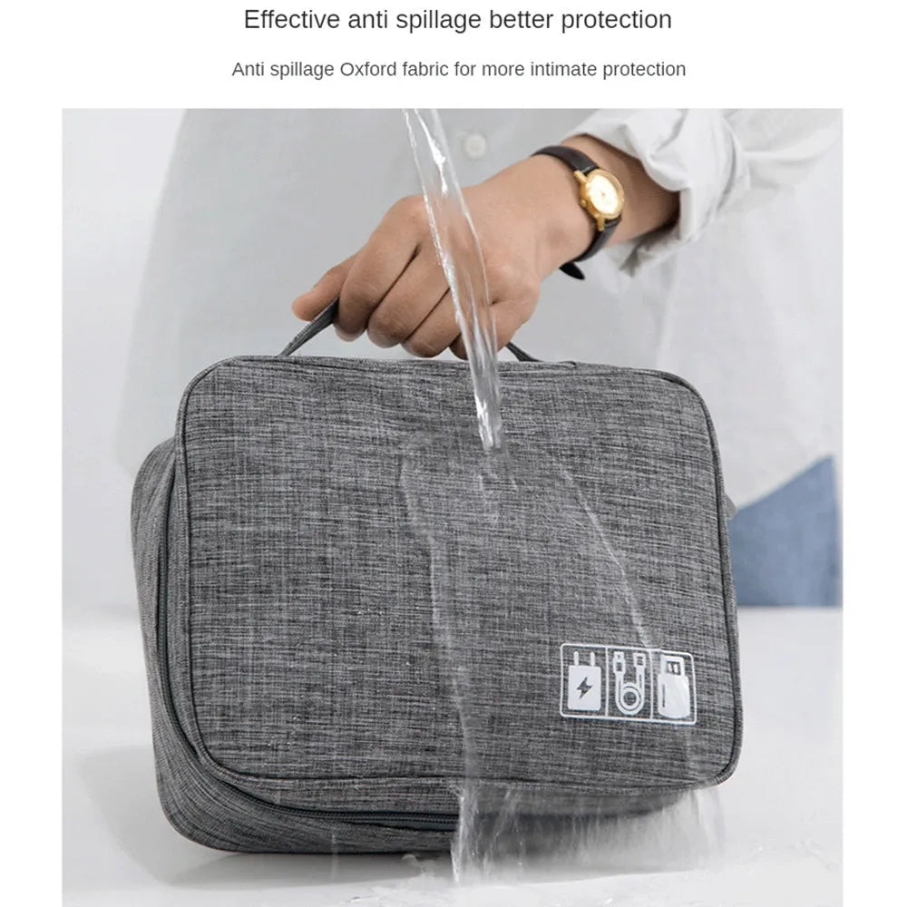 Black travel cable organiser bag open to show mesh pockets, elastic loops, and removable padded dividers inside.