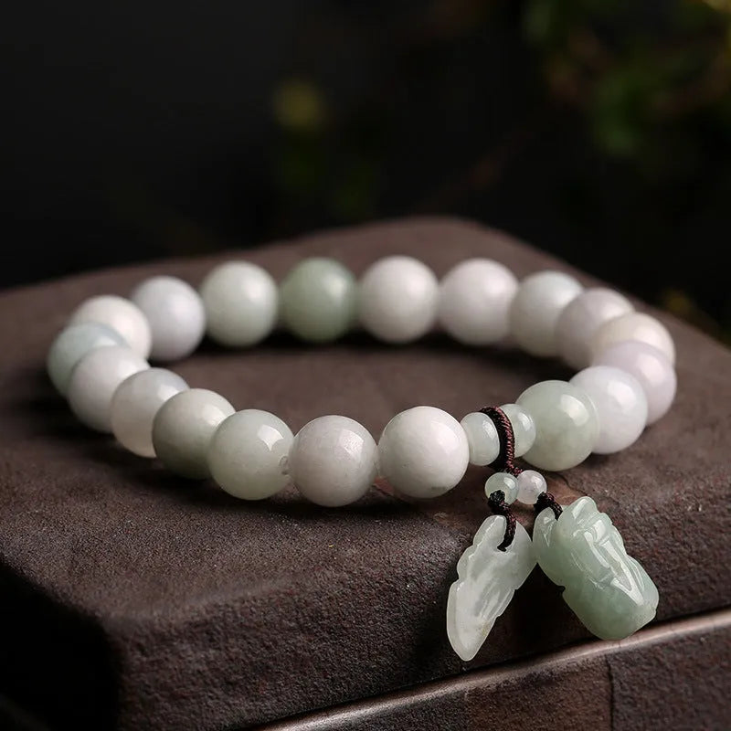 Natural green jade bracelet with a geometric hanging pendant showing choice of symbolic designs.