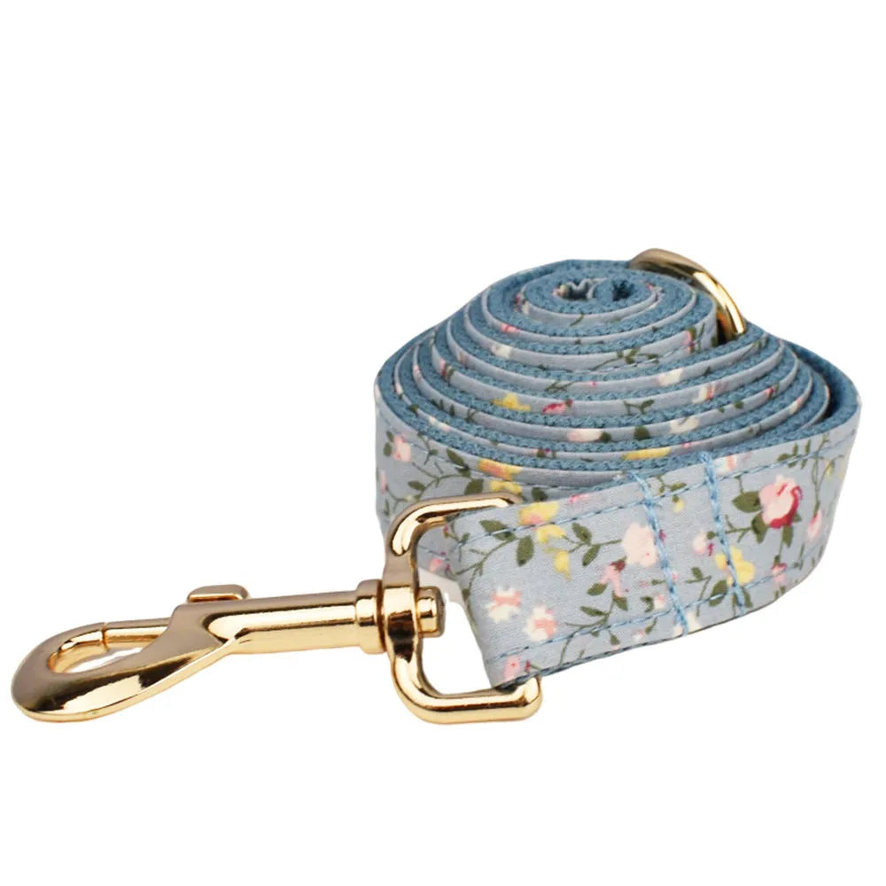 Blue floral pattern dog collar accessories set with adjustable collar, matching leash, bow, vest, and poop bag