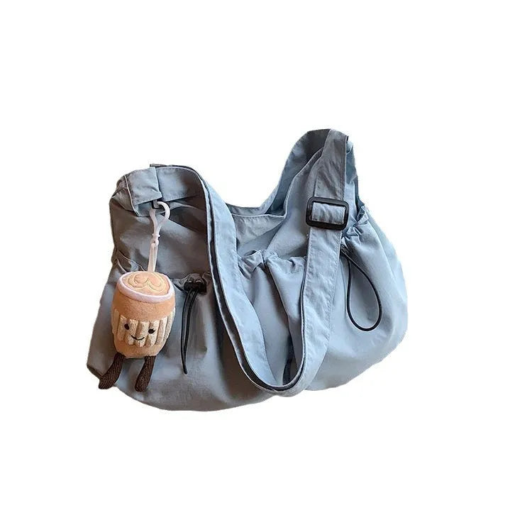 Soft green pleated polyester crossbody bag folded next to a mobile phone showing internal pocket.