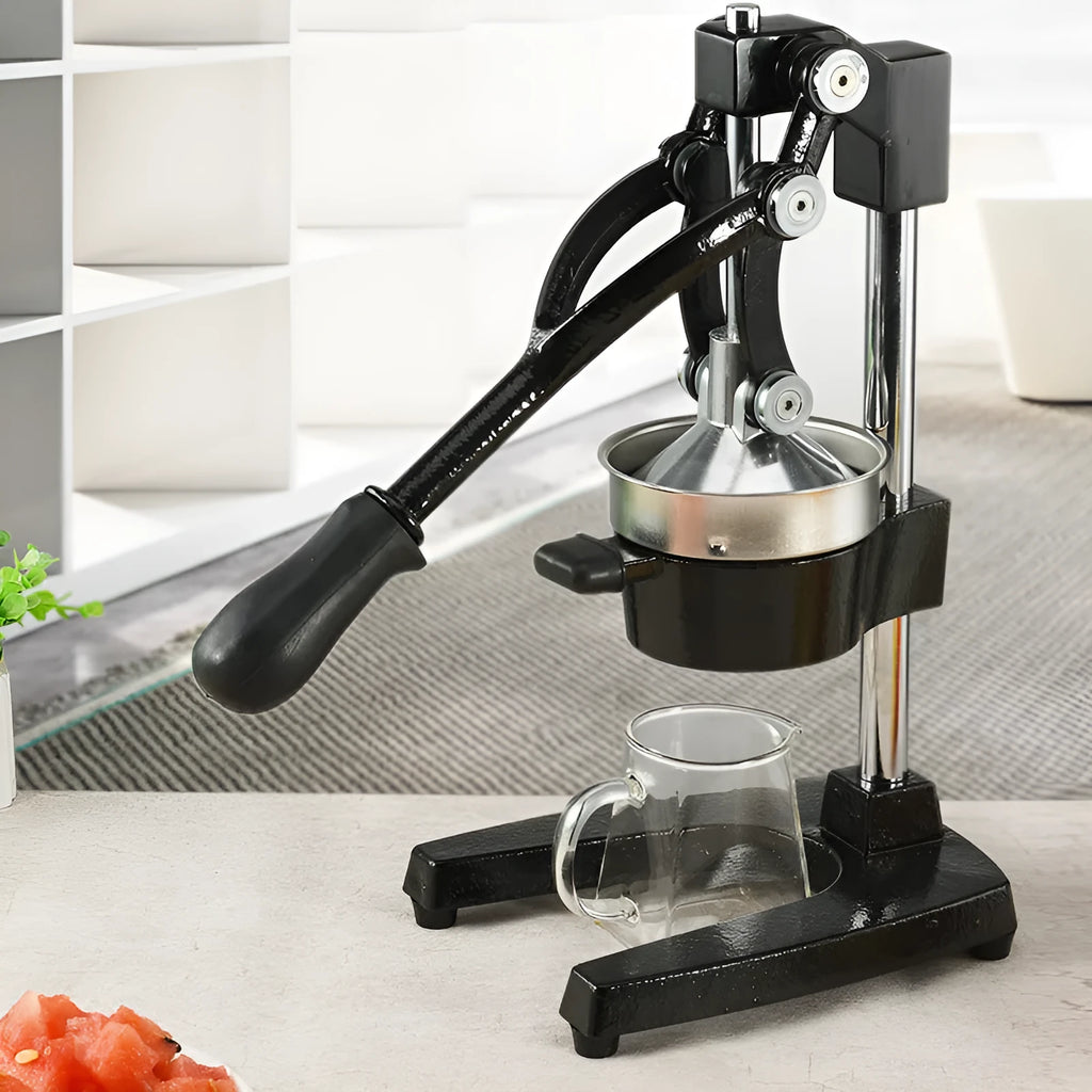 Tall black cast iron manual citrus juicer with stainless steel funnel on a kitchen counter.