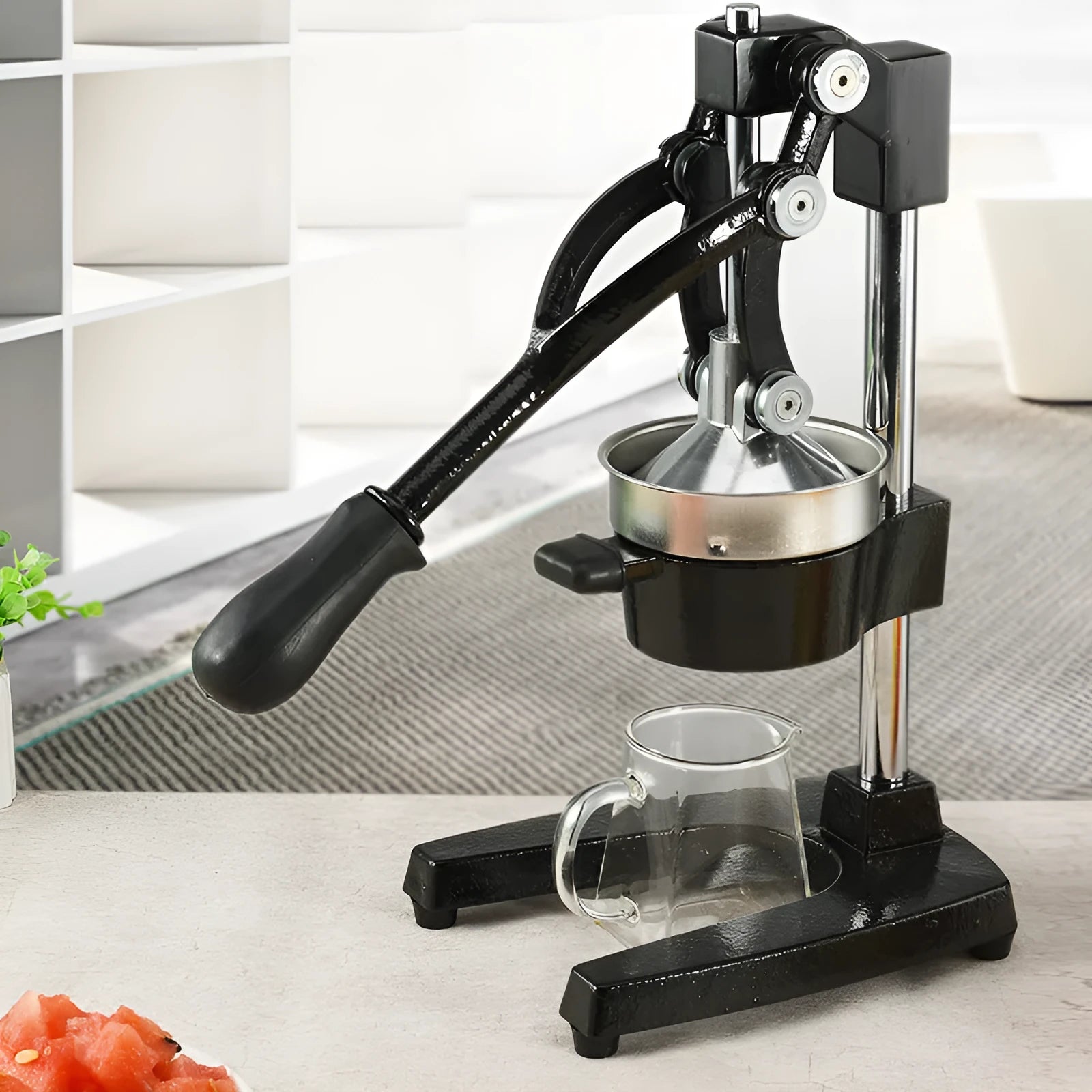 Tall black cast iron manual citrus juicer with stainless steel funnel on a kitchen counter.