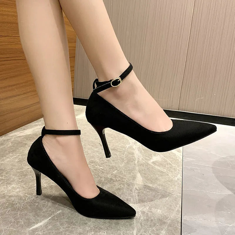 Women's black stiletto heel pump shoes with a buckle and skull pattern lining on a white background.