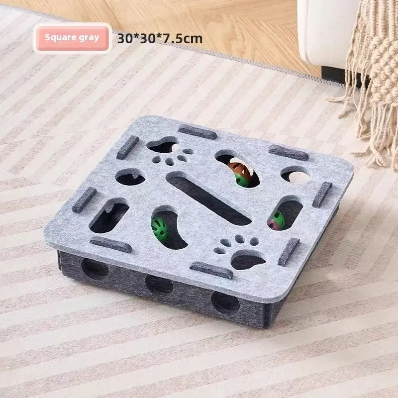 Green brown felt square cat toy with a hole in the centre on a wooden floor.