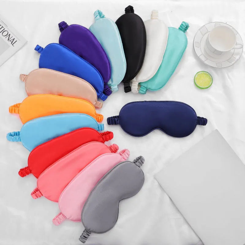 Double-sided silk-like sleep mask in rayon elastic satin shown in multiple colour options on a grey background.