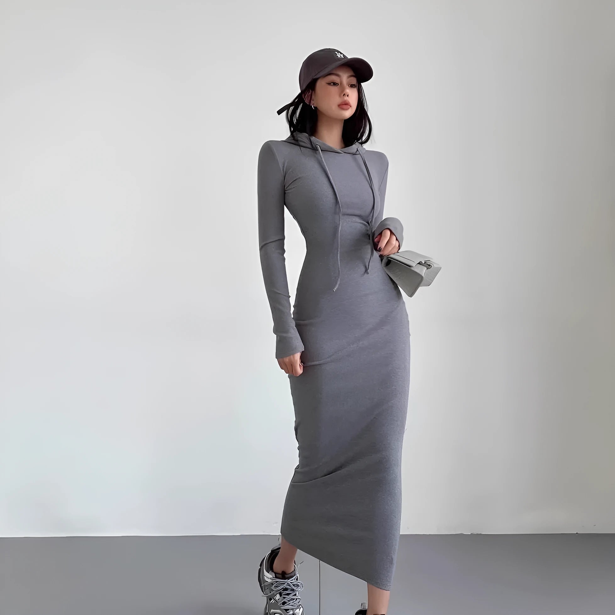 A woman modelling a grey hooded long sleeve sheath dress with a high waist.