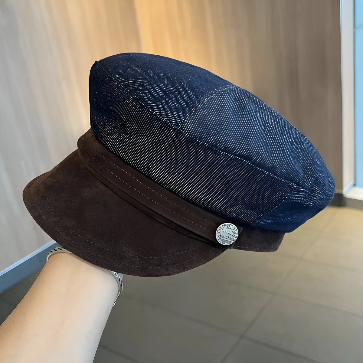 Dark blue denim newsboy cap with an adjustable strap, shown on a model