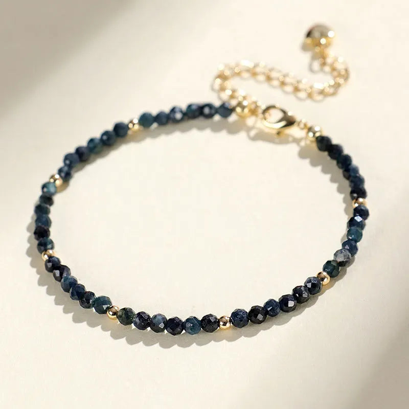 Close-up of a blue tourmaline beaded bracelet with metallic spacer beads on a woman's wrist.