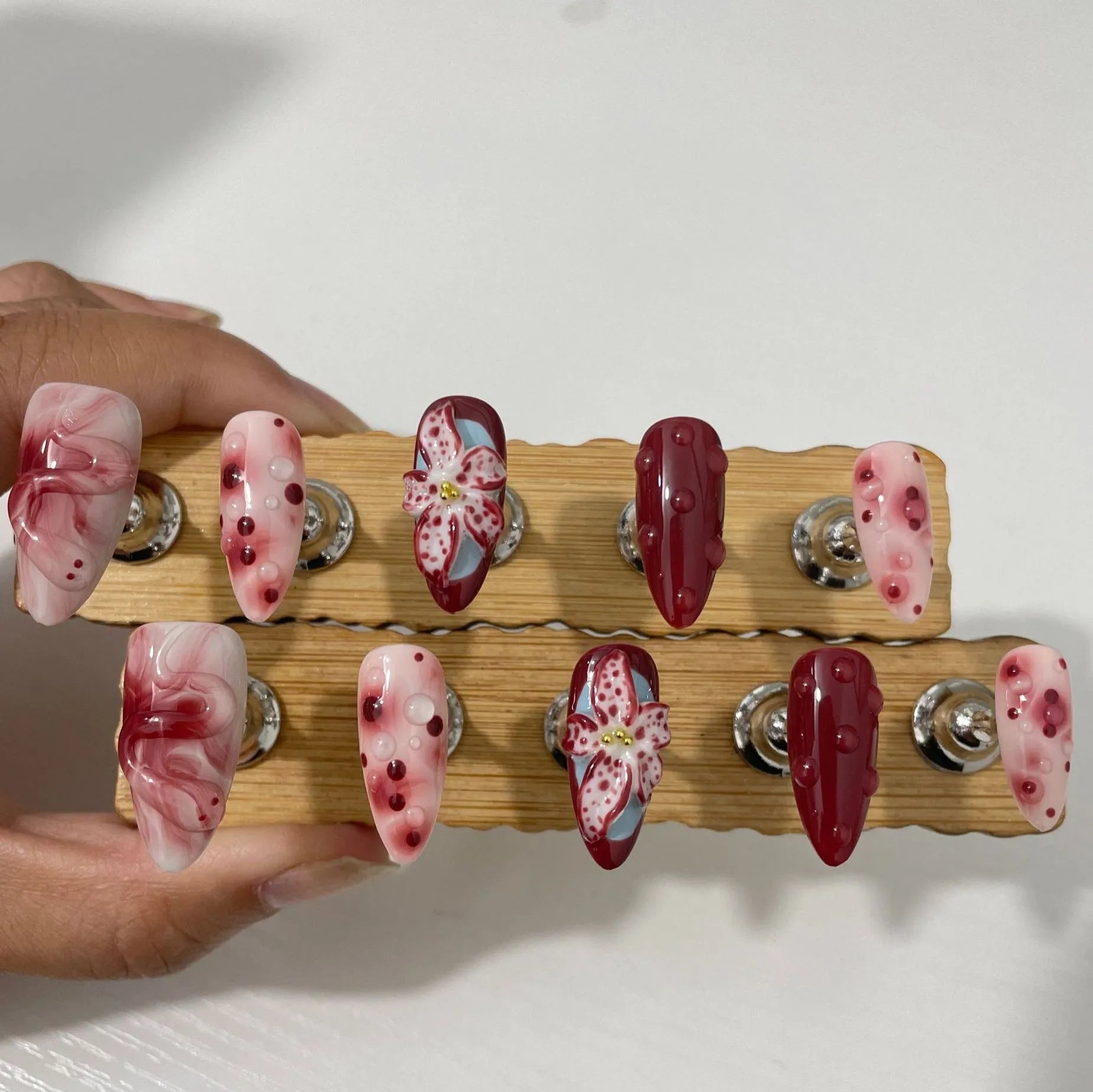 Almond colour artificial nails with 3D carved floral designs including roses and tulips
