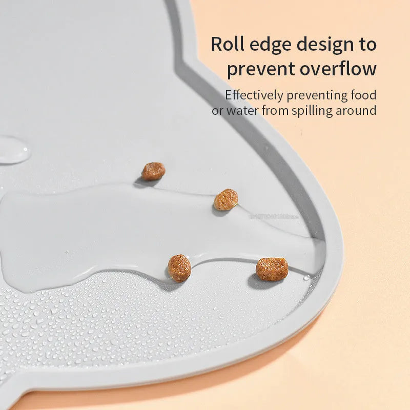 Blue silicone pet feeding mat with cat head shape under food and water bowls.