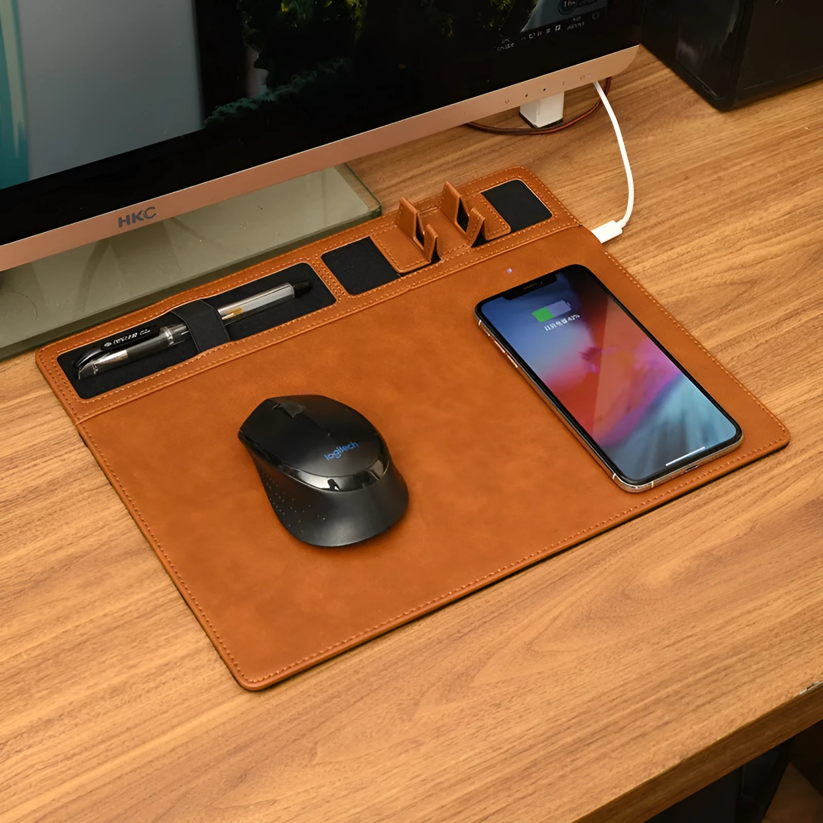 Pink wireless charging mouse pad with integrated phone holder on a wooden desk.