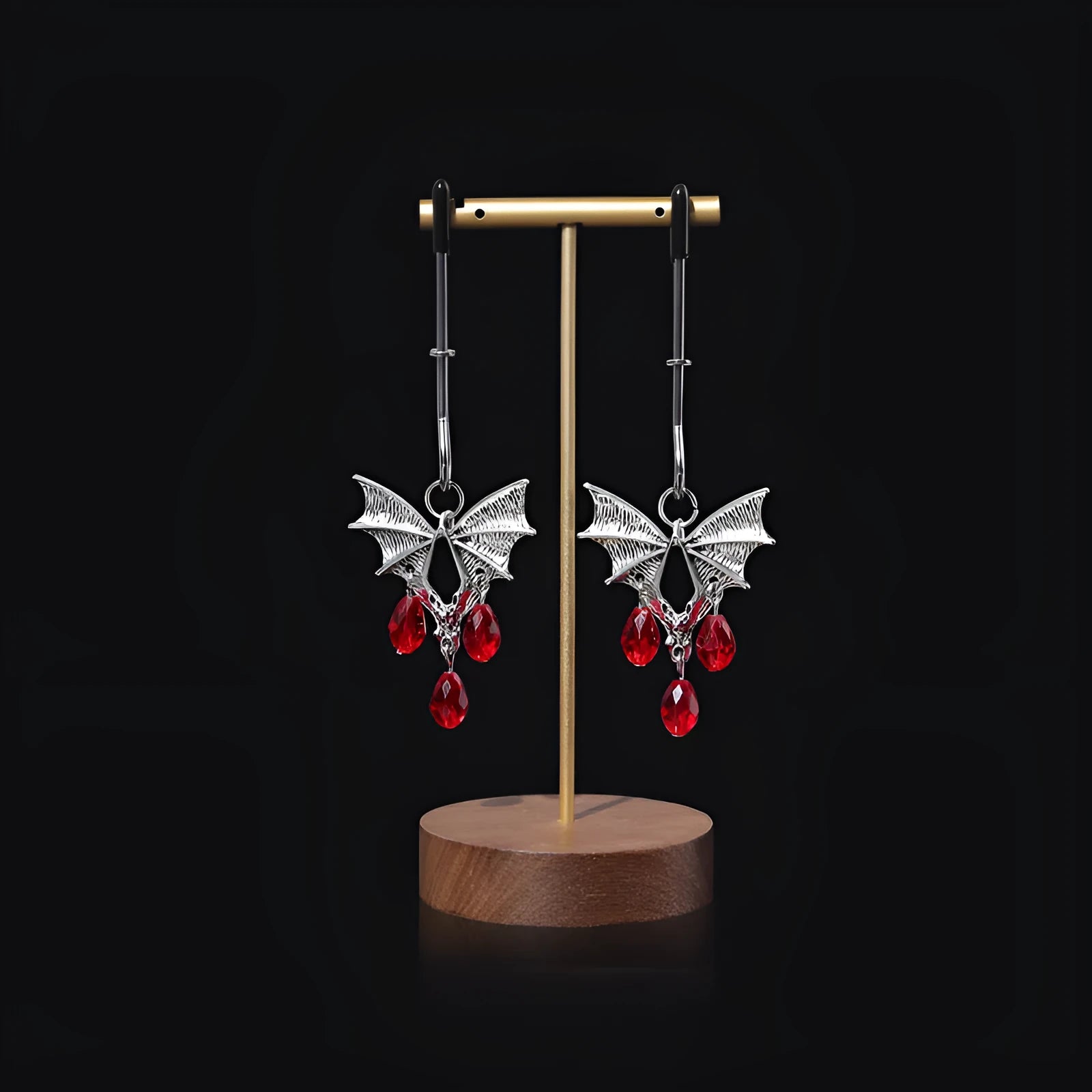 A pair of silver metal bat-shaped adjustable nipple clamps on a plain background.