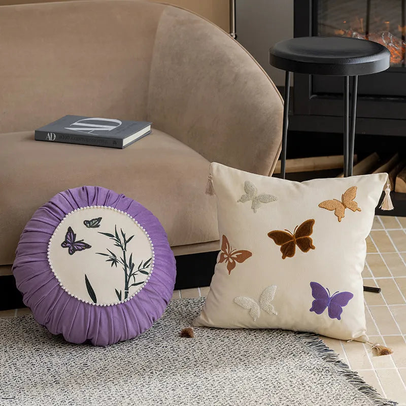 Square beige couch pillow with detailed Chinese-style butterfly embroidery.