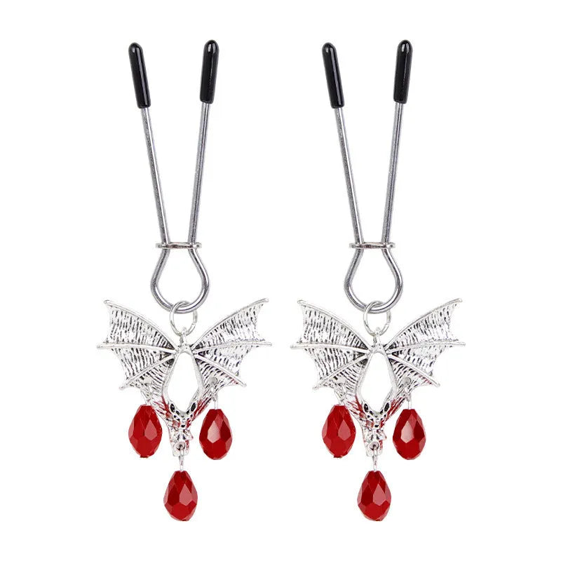 A pair of silver metal bat-shaped adjustable nipple clamps on a plain background.