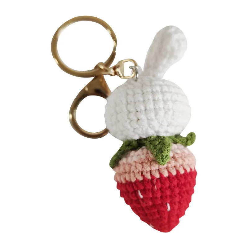 White hand-woven wire pendant with a cartoon rabbit strawberry design and an attached key.