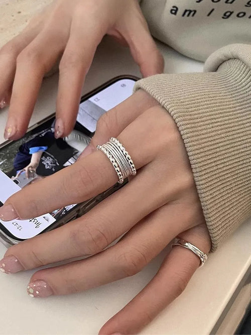 Copper-toned geometric alloy ring with a woven twisted design and adjustable opening.