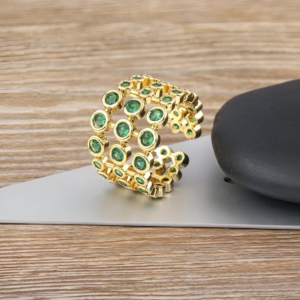 Gold-coloured exaggerated wide band ring with three-layer design and full green zircon stone setting.