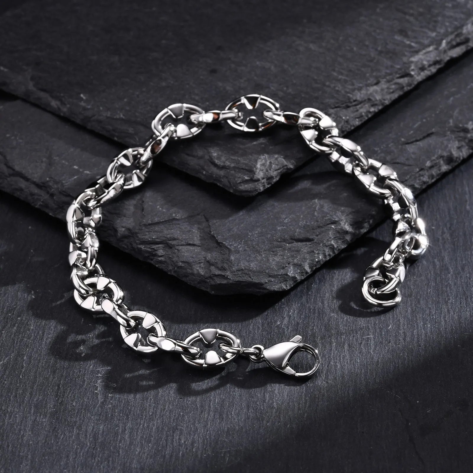 Handmade thick stainless steel geometric chain bracelet for men on a grey background.