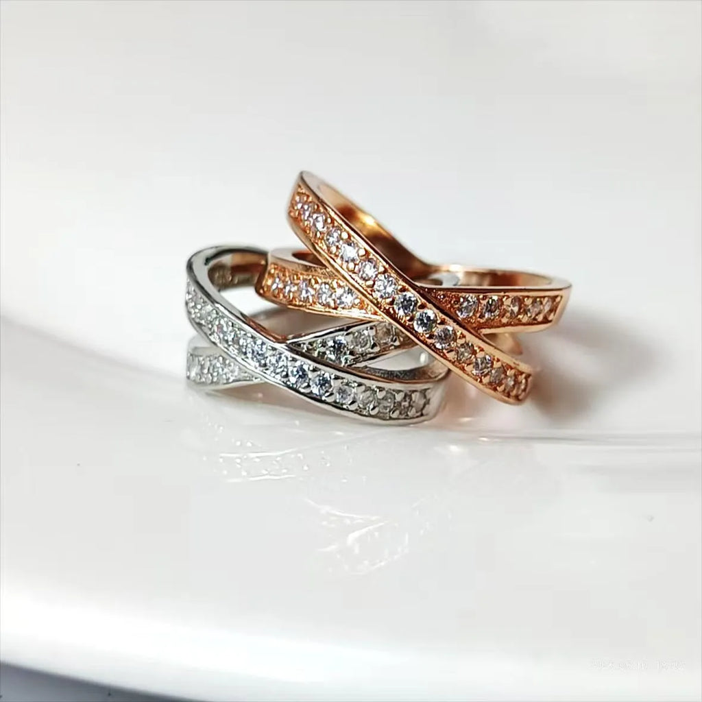 Simple metal cross ring with micro-inlaid zircon detail in silver or rose gold on a finger.