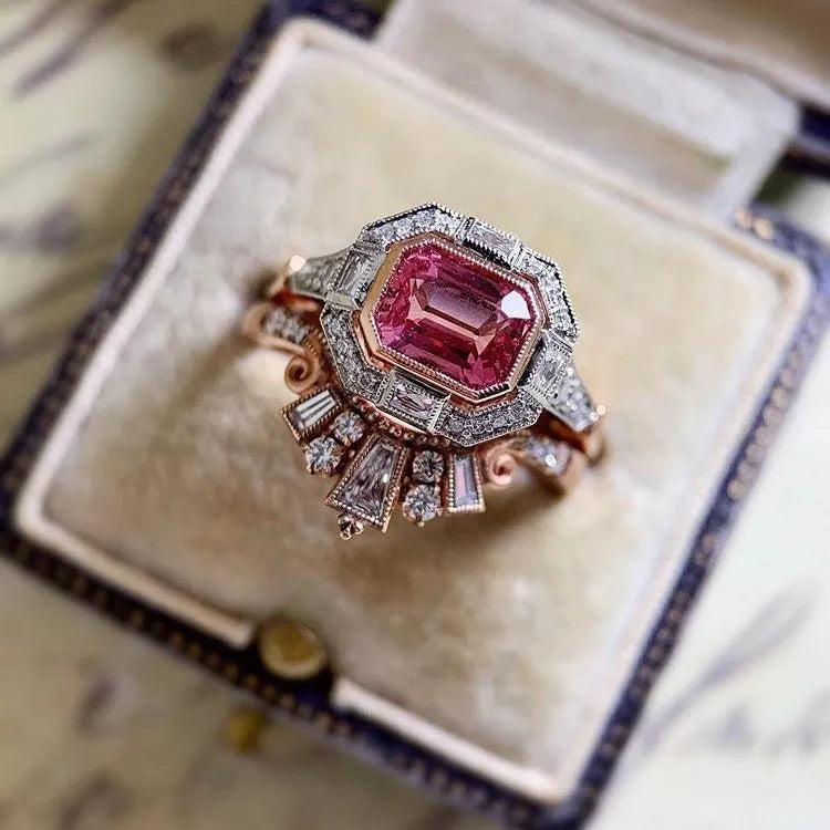 Rose gold coloured geometric women's alloy ring with a ruby detail on a white background.