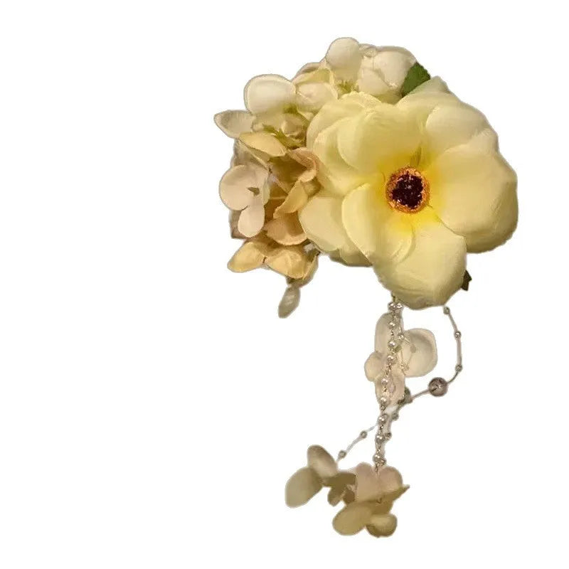 Close-up of a handmade floral tassel hair clip in yellow with a side clip.