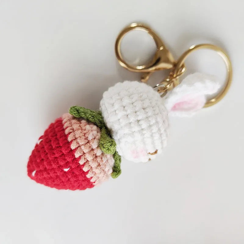 White hand-woven wire pendant with a cartoon rabbit strawberry design and an attached key.