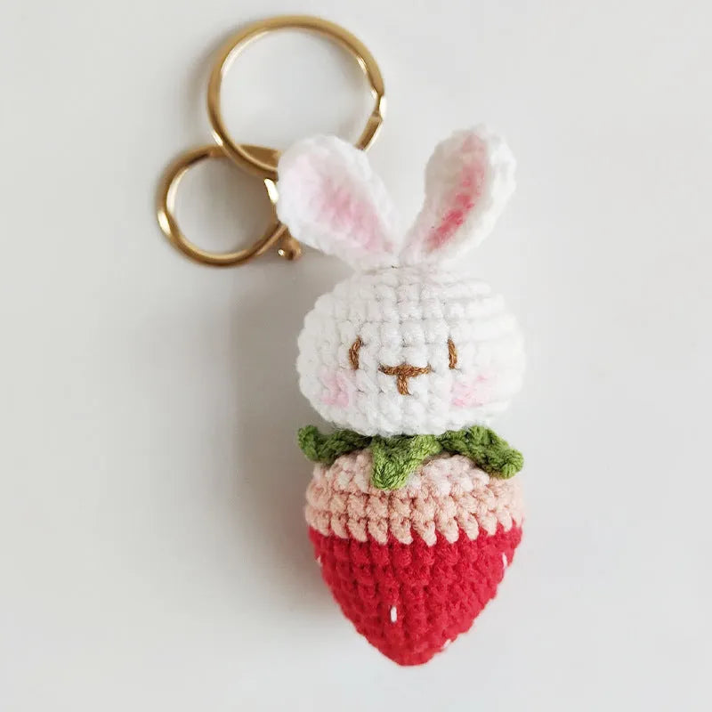White hand-woven wire pendant with a cartoon rabbit strawberry design and an attached key.