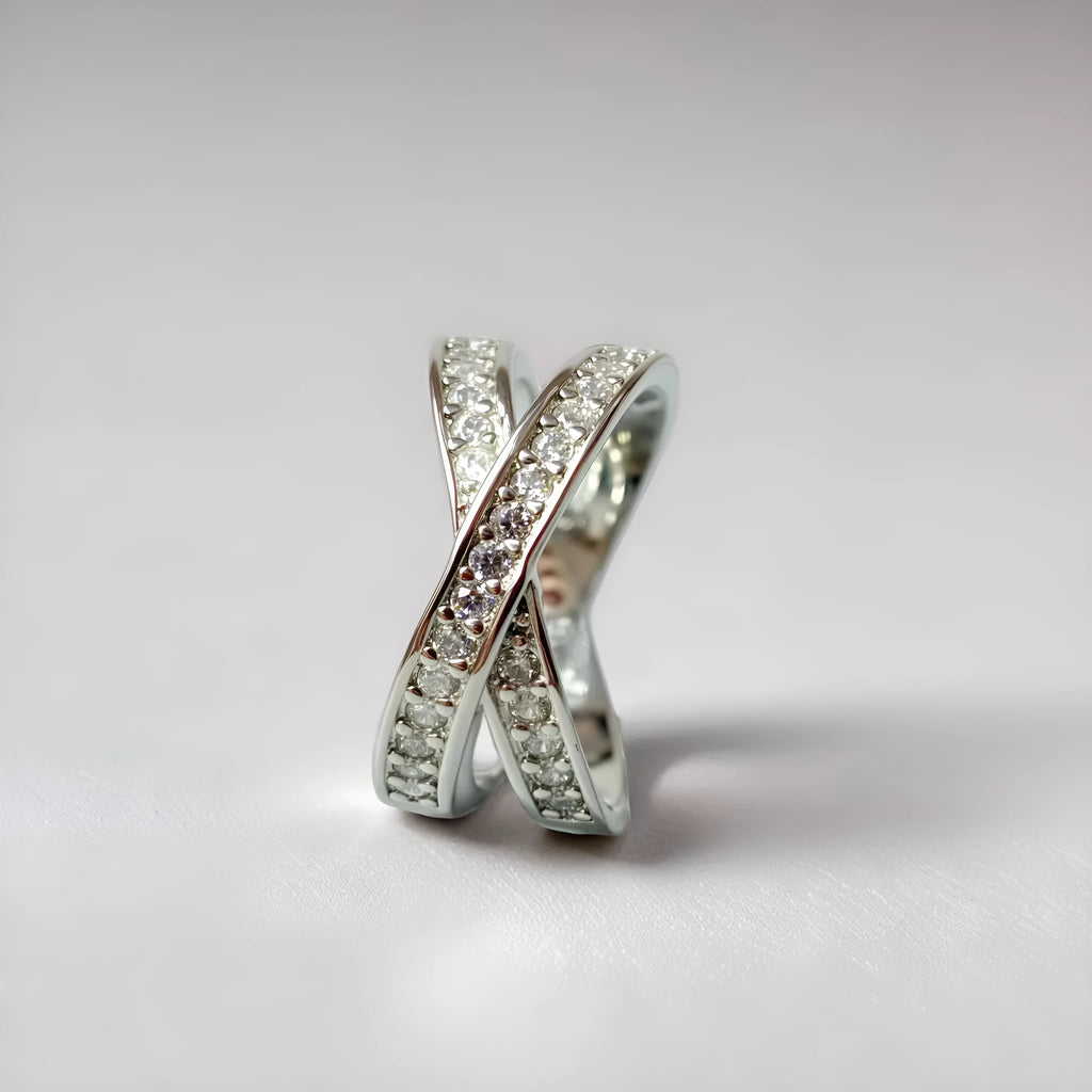 Simple metal cross ring with micro-inlaid zircon detail in silver or rose gold on a finger.