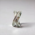 Simple metal cross ring with micro-inlaid zircon detail in silver or rose gold on a finger.