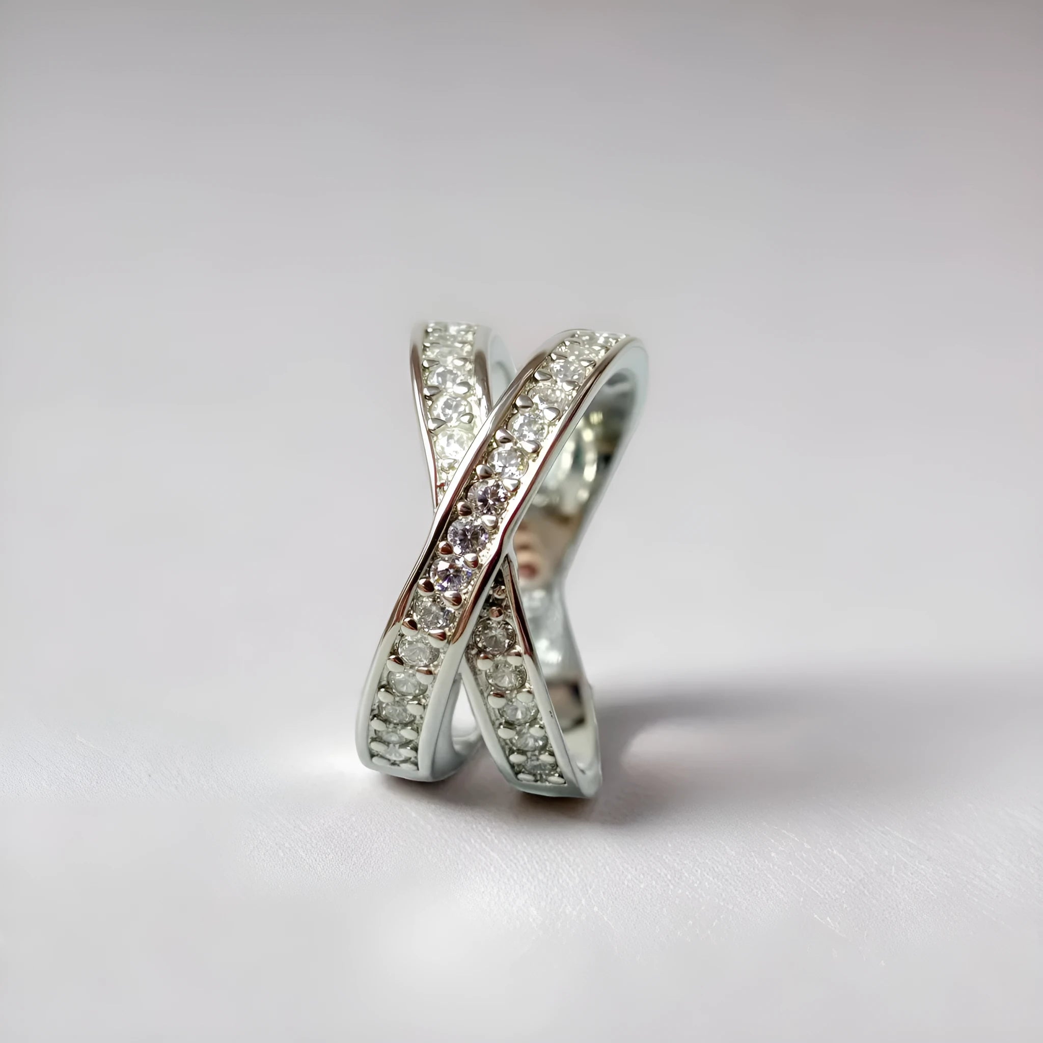 Simple metal cross ring with micro-inlaid zircon detail in silver or rose gold on a finger.