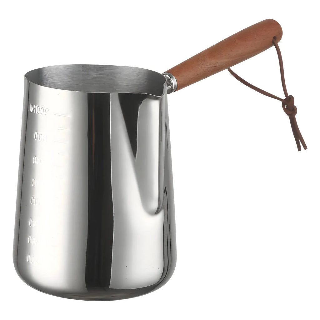 Stainless steel milk jug with measurement scale and wooden handle on a counter.