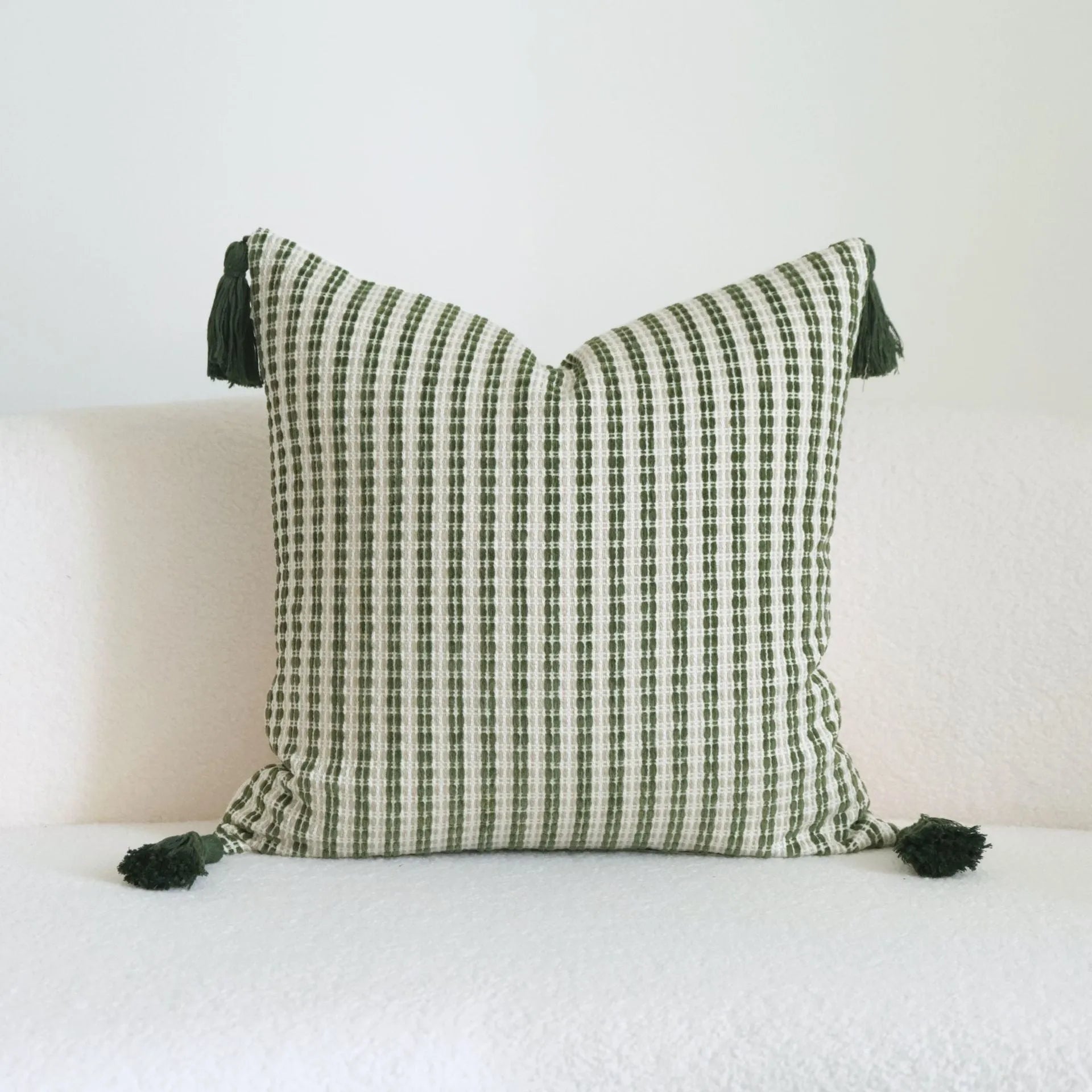 Green decorative pillow with botanical embroidery on cotton linen fabric, shown with tassel and bead details.
