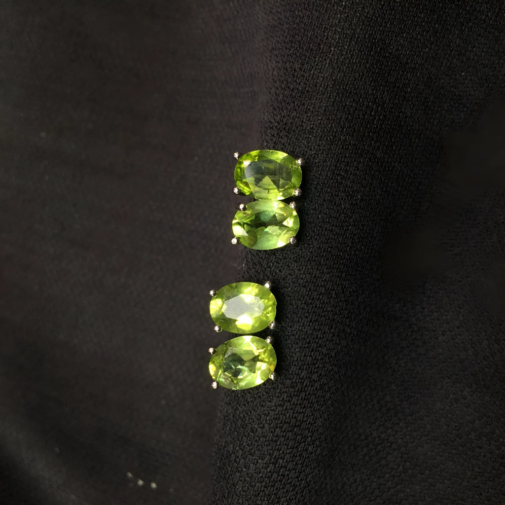 Close-up of natural grass green olivine stud earrings in S925 sterling silver settings.